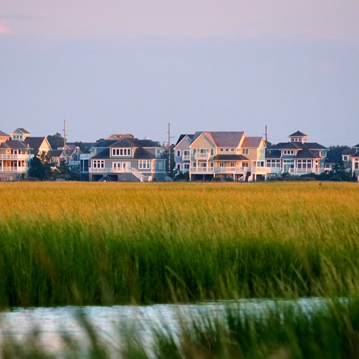 a row of houses in the distance with a body of water in the foreground