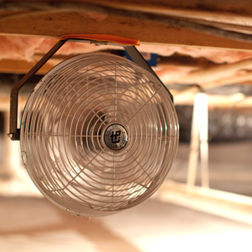 a fan hanging from the ceiling of a crawl space